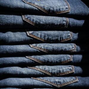 Neatly stacked blue jeans with visible price tag in retail setting.